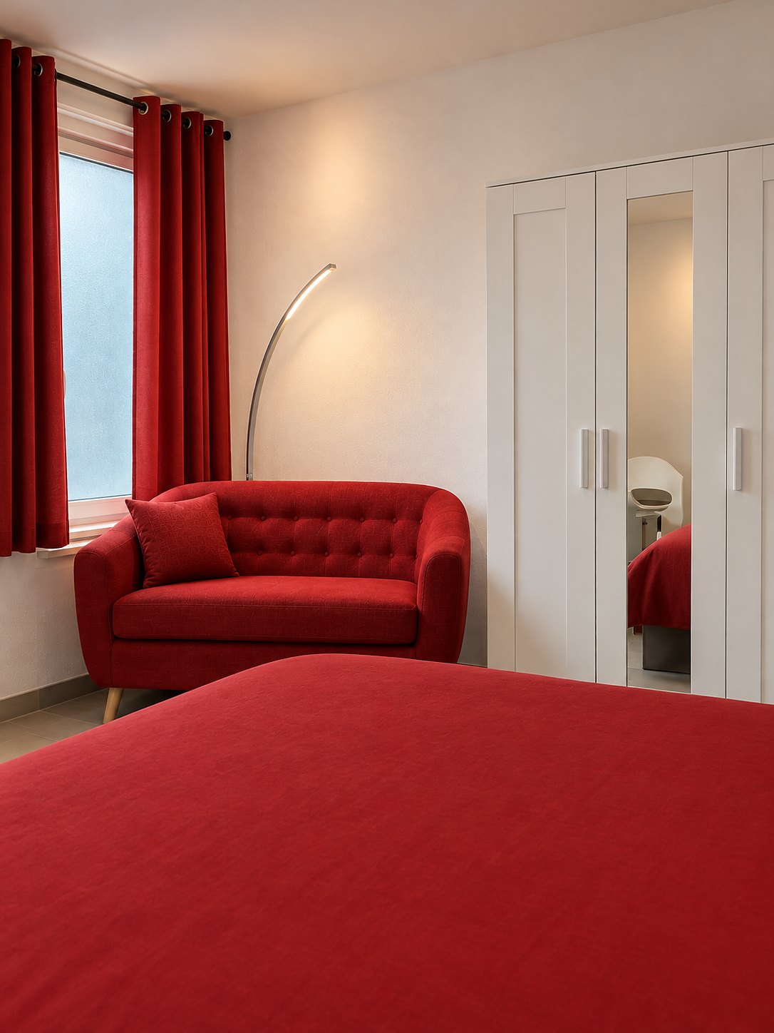 La chambre rouge : lit double, canapé rouge et armoire à miroir